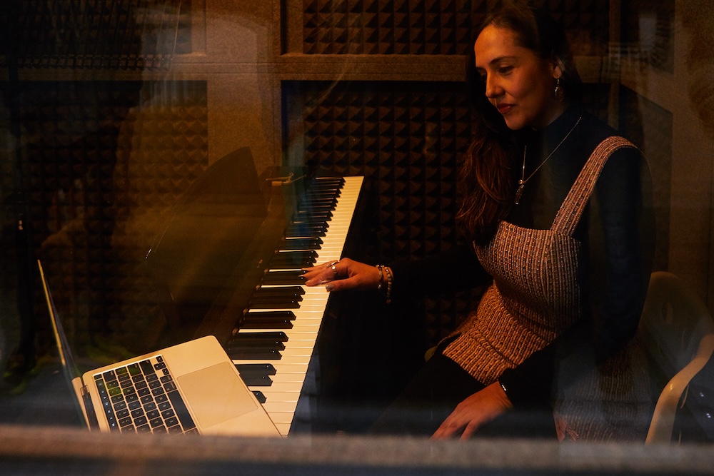 singing teacher playing keyboard in sound booth