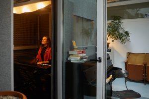 singer smiling in vocal pod booth with door open