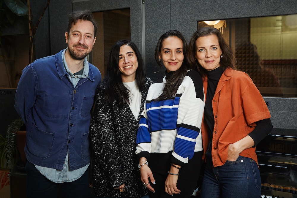 four singing teachers and vocal coaches smiling at the camera in front of sound booth
