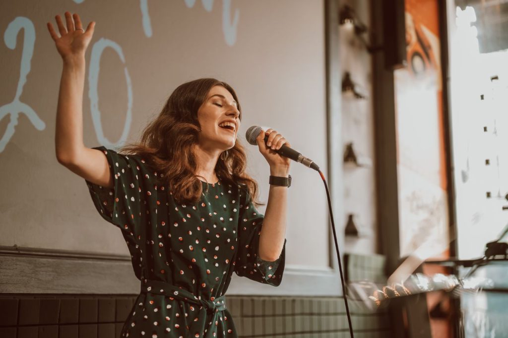 Female musician singing passionately with a microphone indoors.