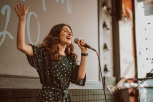 Female musician singing passionately with a microphone indoors.